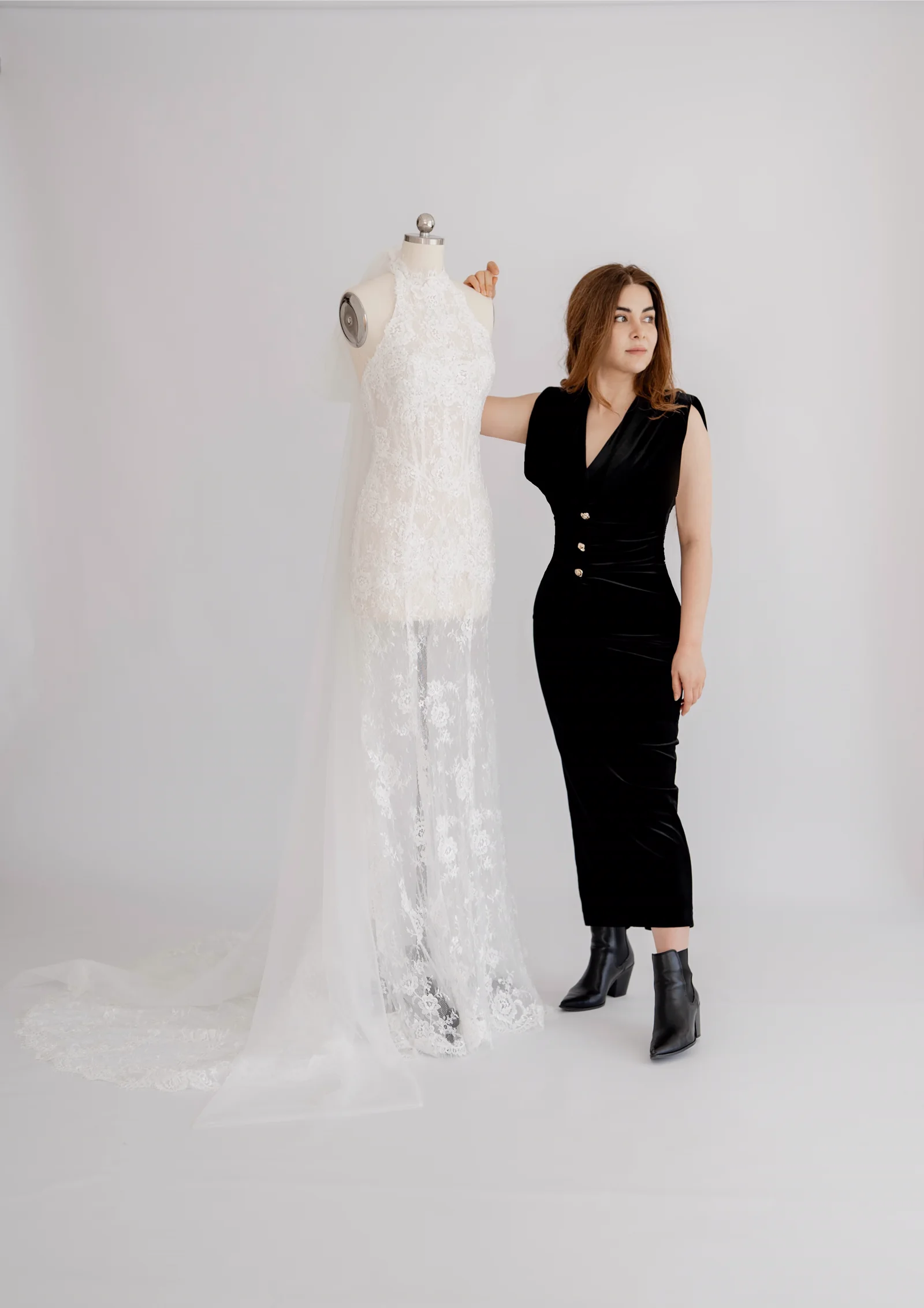 Shirin, founder and bridal designer of SHIRIN Atelier, beside a lace wedding gown